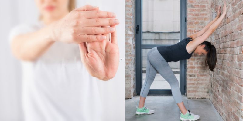 Woman on the left stretching her hand/ wrist, woman on the right doing a back stretch on a wall
